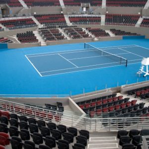 Un campo da tennis indoor completamente vuoto, visto dalle tribune, anch'esse senza spettatori