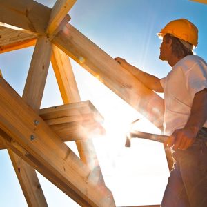 Un operaio sta lavorando alla struttura in legno di un tetto con il sole al centro della foto