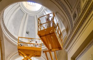 Dei restauratori stanno compiendo dei lavori di restauro in una chiesa su due ponteggi