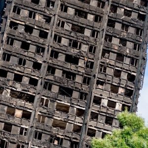 Vista ravvicinata della Grenfell Tower di Londra dopo l'incendio. L'orizzonte della fotografia è inclinato e la torre sembra sul punto di crollare