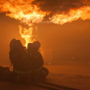 Dettaglio di una casa di campagna che brucia, con le fiamme che escono dalle due finestre