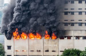 Un edificio in stile brutalista sta bruciando con fiamme che escono dalle finestre e fumo nero che si sprigiona verso l'alto