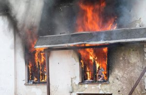 Dettaglio di una casa di campagna che brucia, con le fiamme che escono dalle due finestre