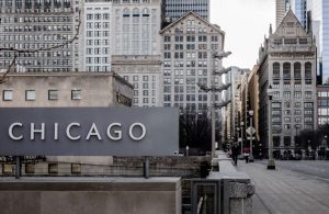 Insegna con la scritta Chicago su una strada della metropoli statunitense, tra palazzi e grattacieli storici