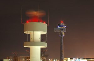 La torre di controllo dell'Aeroporto Internazionale di Dusseldorf di notte, con le luci rosse e, in lontananza, le luci dei terminal
