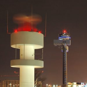 La torre di controllo dell'Aeroporto Internazionale di Dusseldorf di notte, con le luci rosse e, in lontananza, le luci