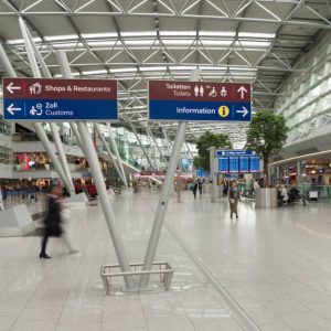 L'interno di uno dei terminal dell'Aeroporto Internazionale di Dusseldorf, con negozi, insegne e persone