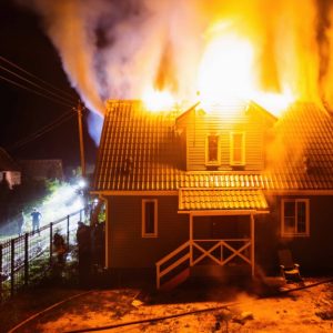 Una casa in legno sta bruciando dal tetto nella notte