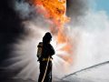 Un pompiere visto di spalle sta cercando di domare un incendio con un getto d'acqua