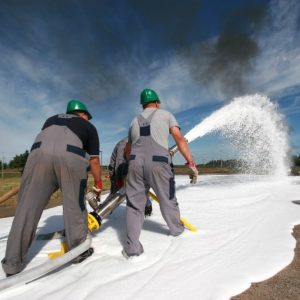 Due uomini con caschetto protettivo verde stanno sparando schiuma su