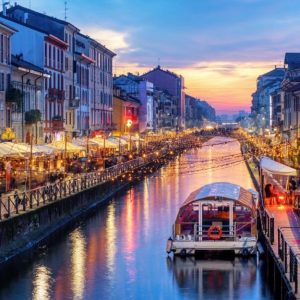 Vista di Porta Garibaldi, a Milano, di tardo pomeriggio, con il sole calante che crea effetti visivi sugli spruzzi d'acqua di una fontana