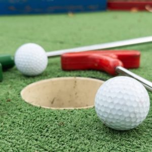 Dettaglio di una buca di un campo da mini-golf, con due palline e due mazze poggiate a terra