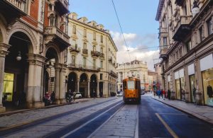 Una via del centro di Torino, con i portici, i negozi, i palazzi nobiliari e un tram che passa