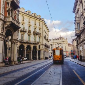 Una via del centro di Torino, con i portici, i negozi, i palazzi nobiliari e un tram che passa